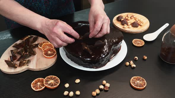 Confectioner is decorating chocolate cake in home modern kitchen.