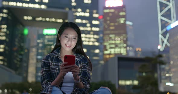 Woman use of smart phone in city at night