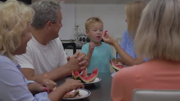 Child Eating Watermelon From Mothers Hands