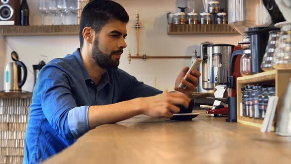 Male business executive using mobile phone while having coffee