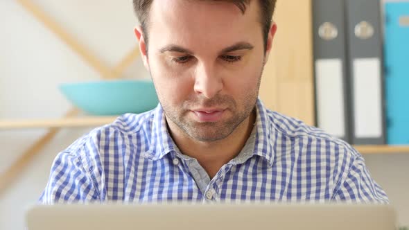 Thumbs Down By Man Working on Laptop
