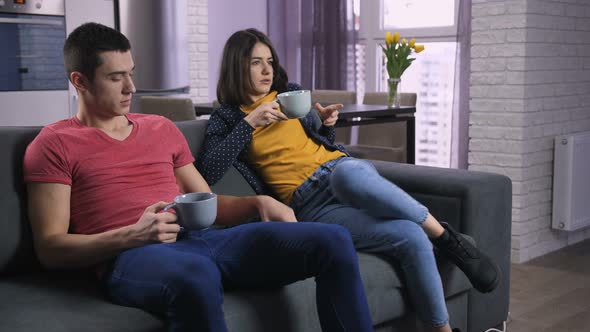 Young Couple Arguing About TV Channels on Sofa