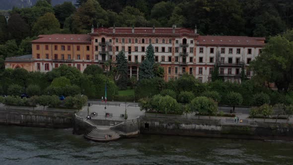 Drone flying over peninsula filled with beautiful buildings at the shore of Lake Como, Italy