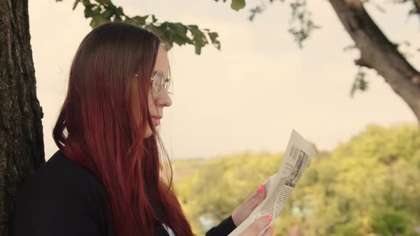 Concentrated Elegant Lady Reading Newspaper in Park