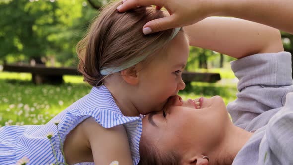 Happy Mother with Baby Girl Lying on Grass in Park