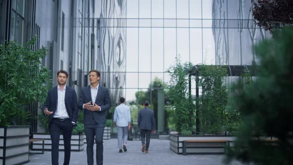 Two Successful Businessmen Walking at Modern Office Building Discussing Project