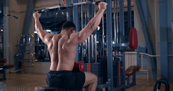 Bodybuilder Doing Exercise on the Simulator in the Gym