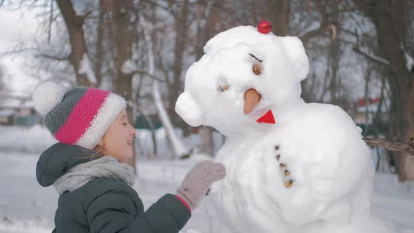 Girl Inserts a Nose on the Snowman