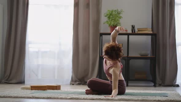 Adult Redhead Woman is Doing Exercises for Spinal at Home Practicing Yoga Training in Living Room