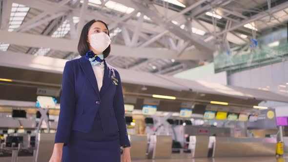 Airliner air hostess crew wearing face mask and walking in airport terminal to the airplanel
