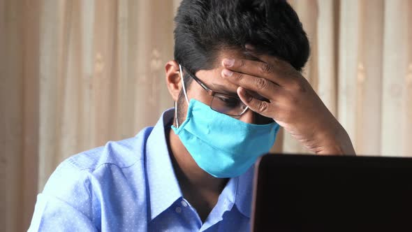 A Sick Young Man with Protective Mask in Face Working on Laptop 