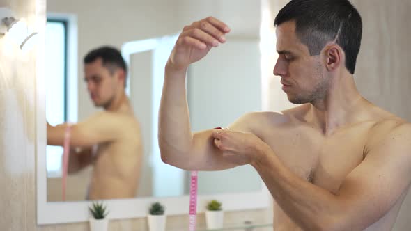 Man in Front of a Mirror Measures Biceps