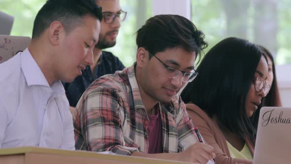 Multiracial Students Listening To Lecture and Making Notes