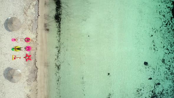 Aerial view of people lying on big inflatable mattresses on beach.