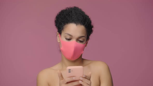 Beauty Portrait of Young African American Woman in Pink Protective Pitta Mask Texting Using