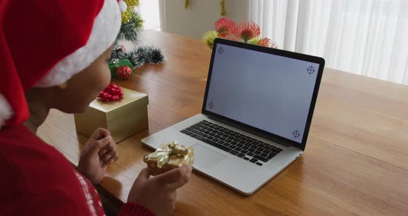 Happy african american plus size woman in santa hat, making video call using laptop at christmas