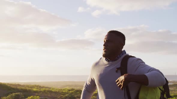 African american man with backpack trying to hitch a lift while walking on the road