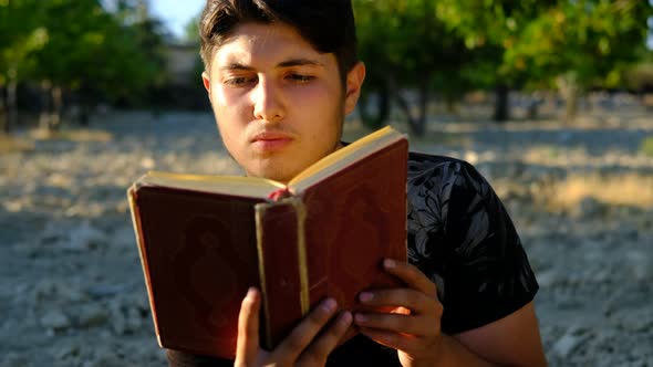 Young Man Reading Quran Outdoors