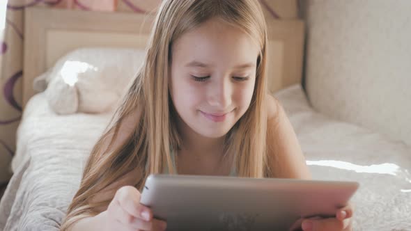 Teenage Girl in Bed Playing a Tablet in Social Internet