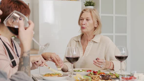 Three Mature Women Chatting during Dinner at Home