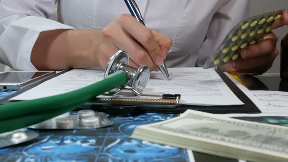 Female Doctor Uses A Smartphone And Writes A Prescription At The Office