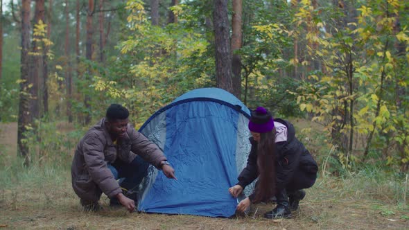 Interracial Travelers Couple Setting Up Camp Tent