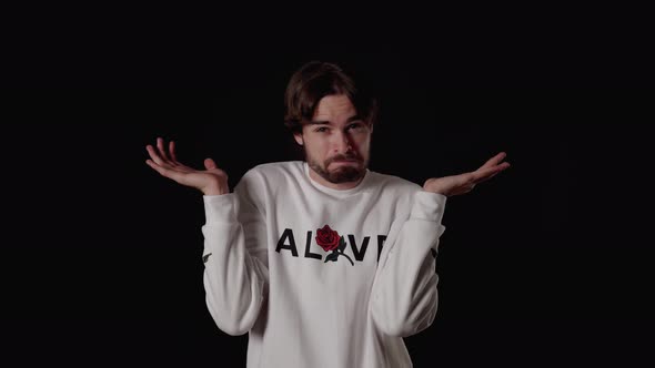 Trendy Young Man making unsure gesture, shoulder shrug, wide, black background