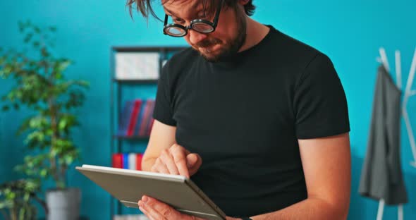 Funny Crazy Strange Boy Sitting on Table with Tablet in Hand Clicks on Screen Shocked