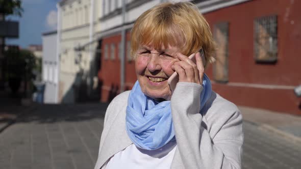 Grandmother Speaking On The Mobile Phone Outdoors In City