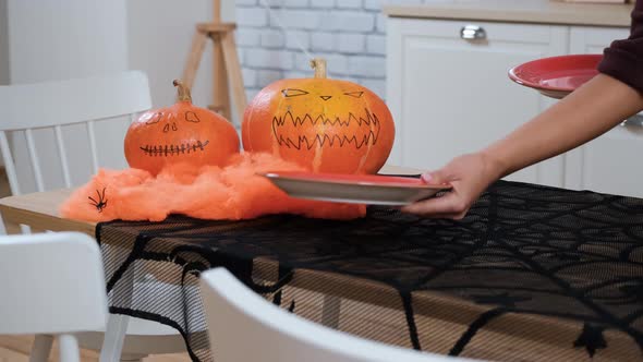 Woman Putting Plates on Festive Halloween Table