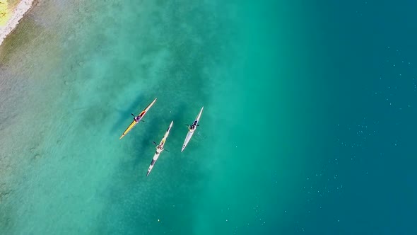 Three kayakers paddle in a scenic mountain lake