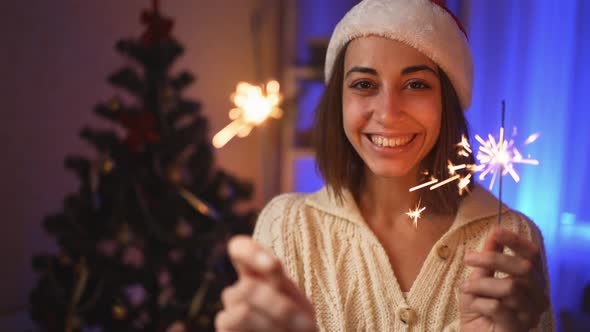 Broll Close Up Portrait Smiling Joyful Girl in Santa Hat with Burning Sparklers at Christmas Eve or