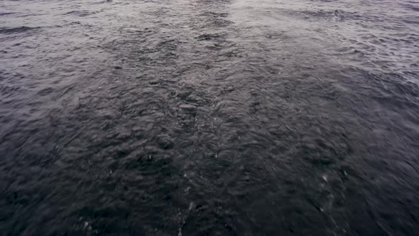 Dark moody water seascape trailing behind the camera, close up.