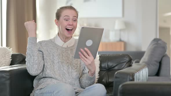 Excited Young Woman Celebrating Success on Tablet at Home 