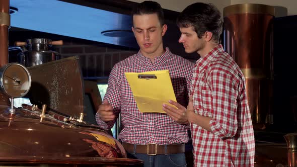 Male Brewer and His Co-worker Examining Brewing Machine at Beer Production