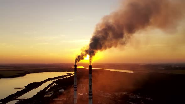 Industrial factory in natural landscape. Dirty smoke in the air at sunset.