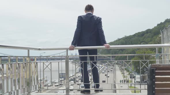 Back View Wide Shot of Suicidal Man Attempting To Commit Suicide Standing at Bridge Fence with Cars