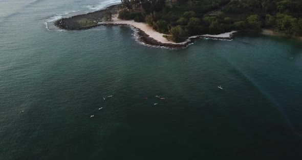 Drone shot of a beach on the North Shore of hawaii. Surfers chilling on the water waiting for waves.
