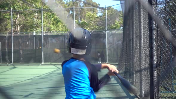 A boy practices baseball at a batting cage.
