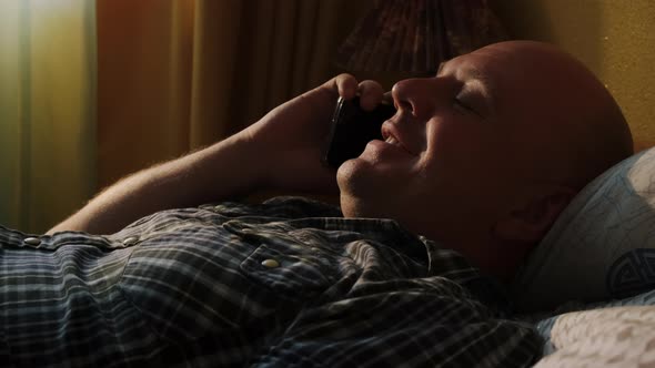 Man Lying in Bed Talking on Smartphone