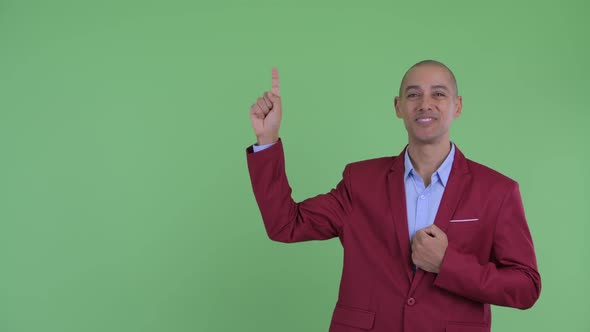 Happy Bald Multi Ethnic Businessman Talking While Pointing Up