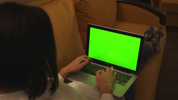 Young Woman Using Laptop with Green Screen Lying on the Couch Sofa at the Home