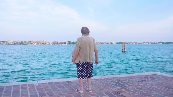 Elderly Woman Traveler Stands Looking at Venice Lagoon