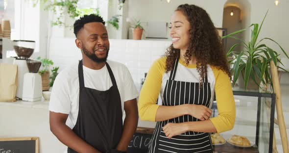 Portrait of happy african american male cafe owner and biracial female barista at cafe