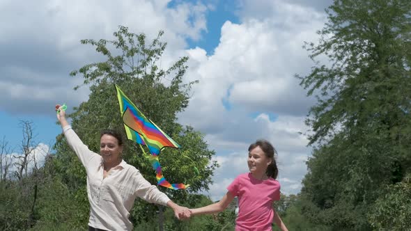 Mother with kid run with a kite. 