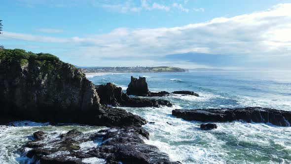 Unique FPV flying past towering basalt rock formation above a rugged seascape coastline. Moving dron