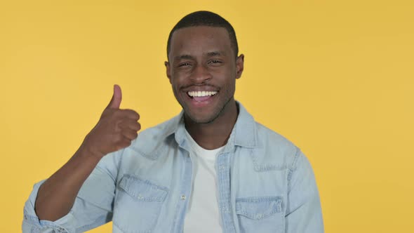 Young African Man with Thumbs Up, Yellow Background 