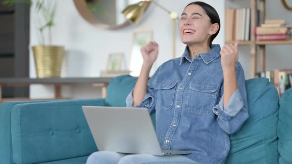 Excited Latin Woman Celebrating Success on Laptop