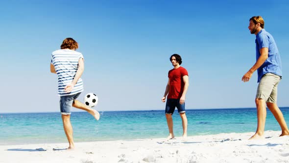 Friends playing football at beach