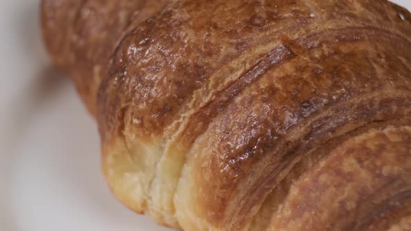 Croissant on white plate rotating in front of camera on black background